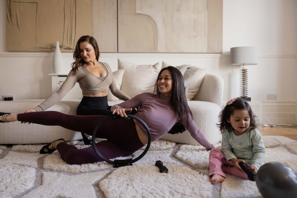 PBB in home stretching with ring equipment. Paola helps a client stretching with a child in the living room